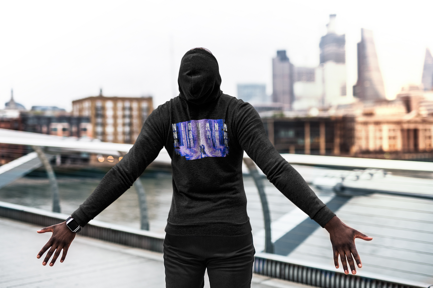 A man in a hoodie stands with arms outstretched, conveying a sense of openness and freedom.