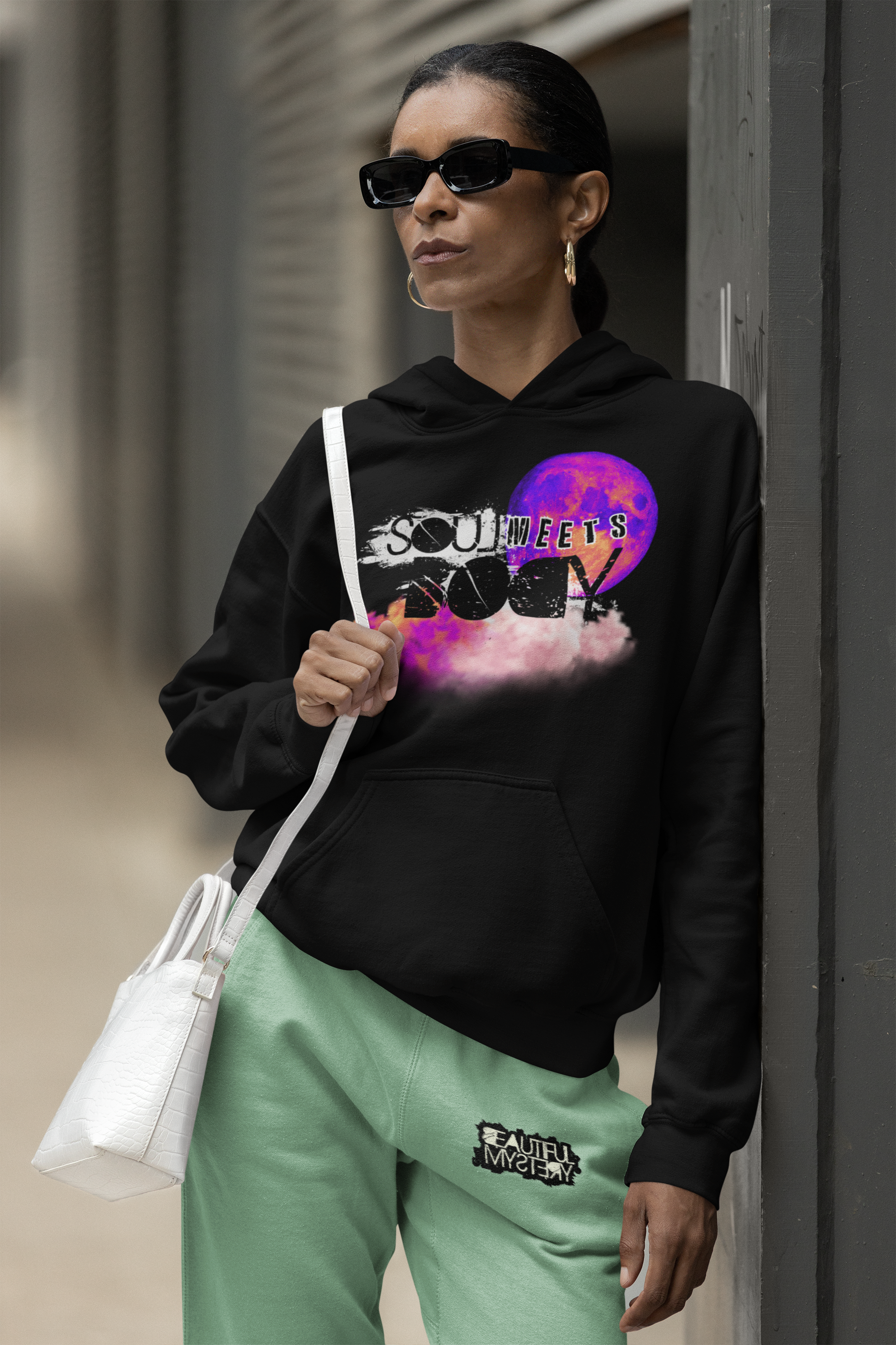 A woman in a hoodie displaying the words "soul rock," standing confidently with a neutral background.