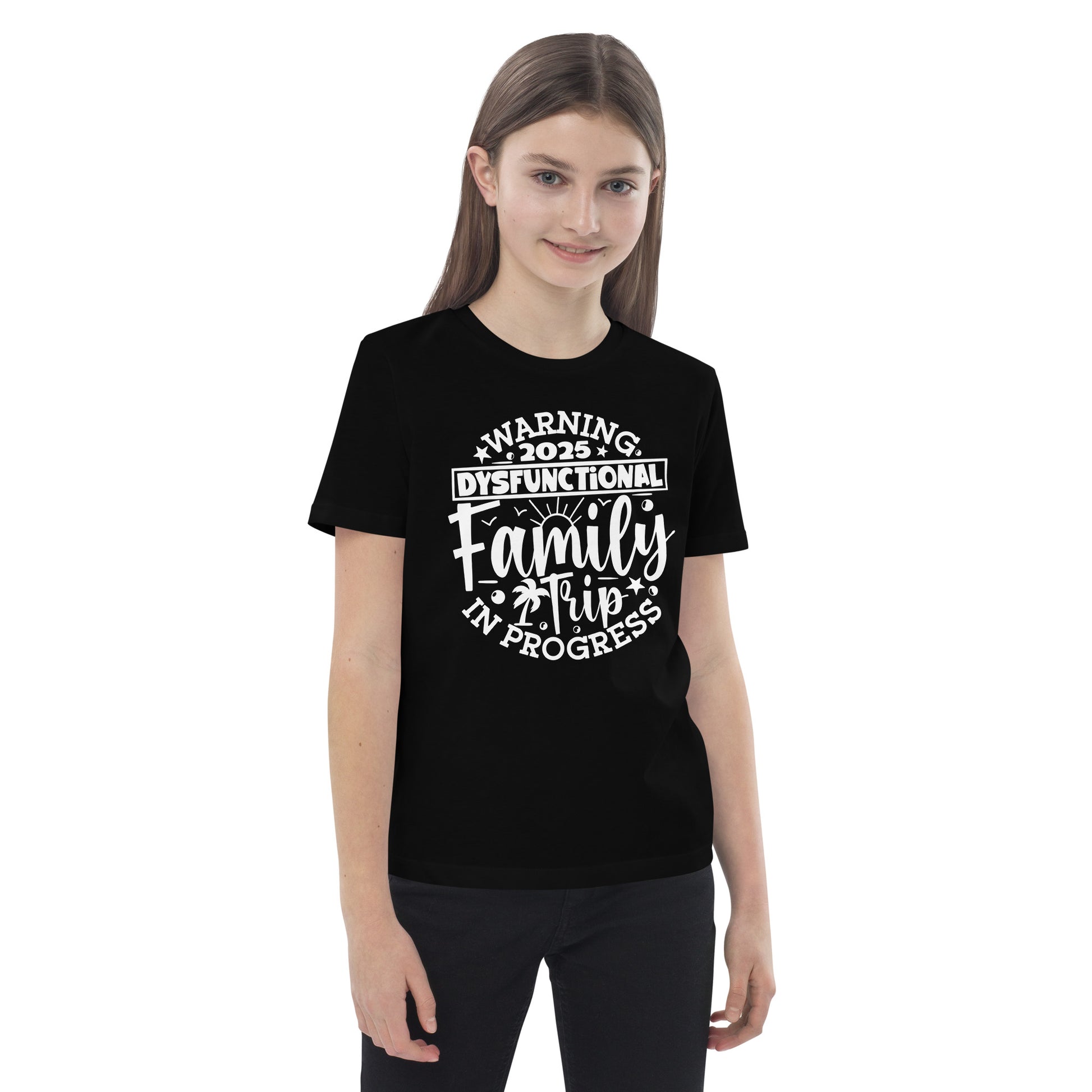  A girl in a t-shirt reading "my family is the greatest gift," smiling and standing in a bright outdoor setting.