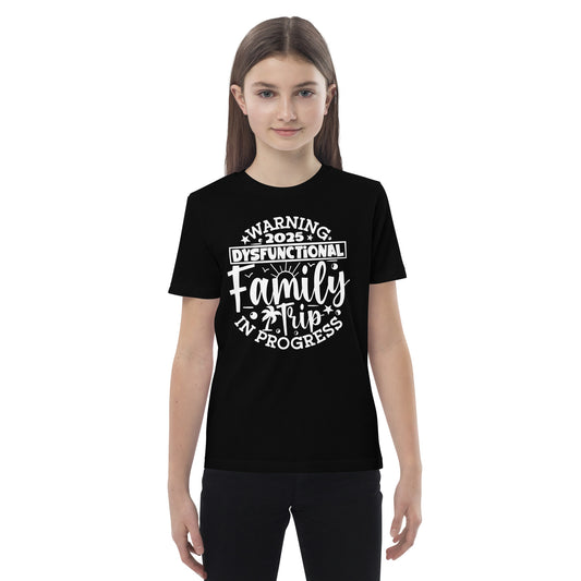 A girl in a t-shirt reading "my family is the greatest gift," smiling and standing in a bright outdoor setting.