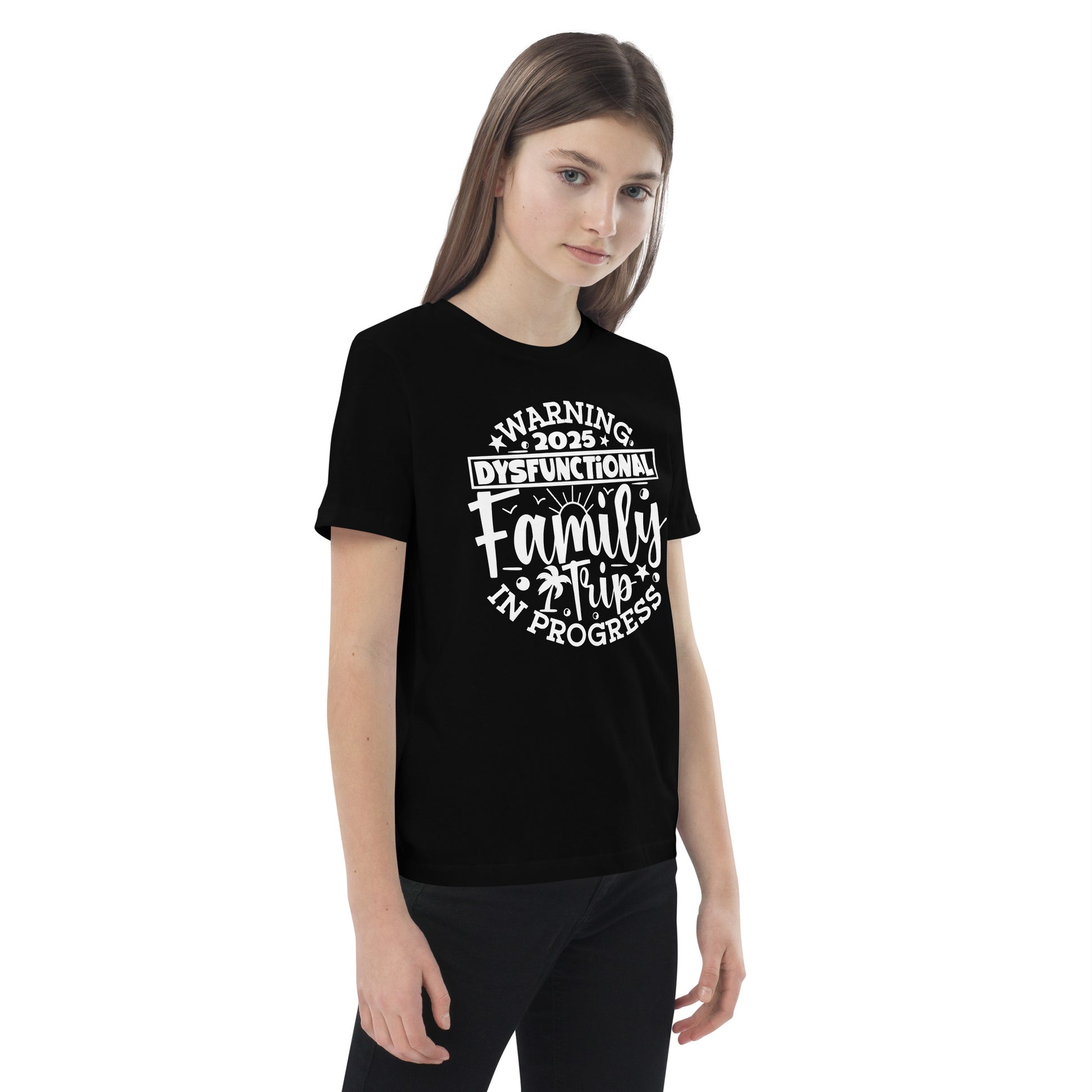  A girl in a t-shirt reading "my family is the greatest gift," smiling and standing in a bright outdoor setting.